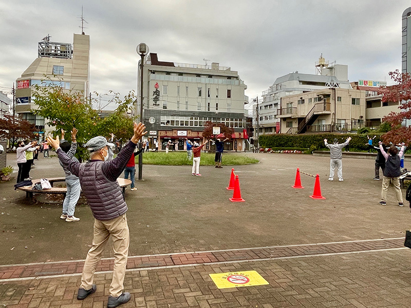駅前でラジオ体操する人々の写真